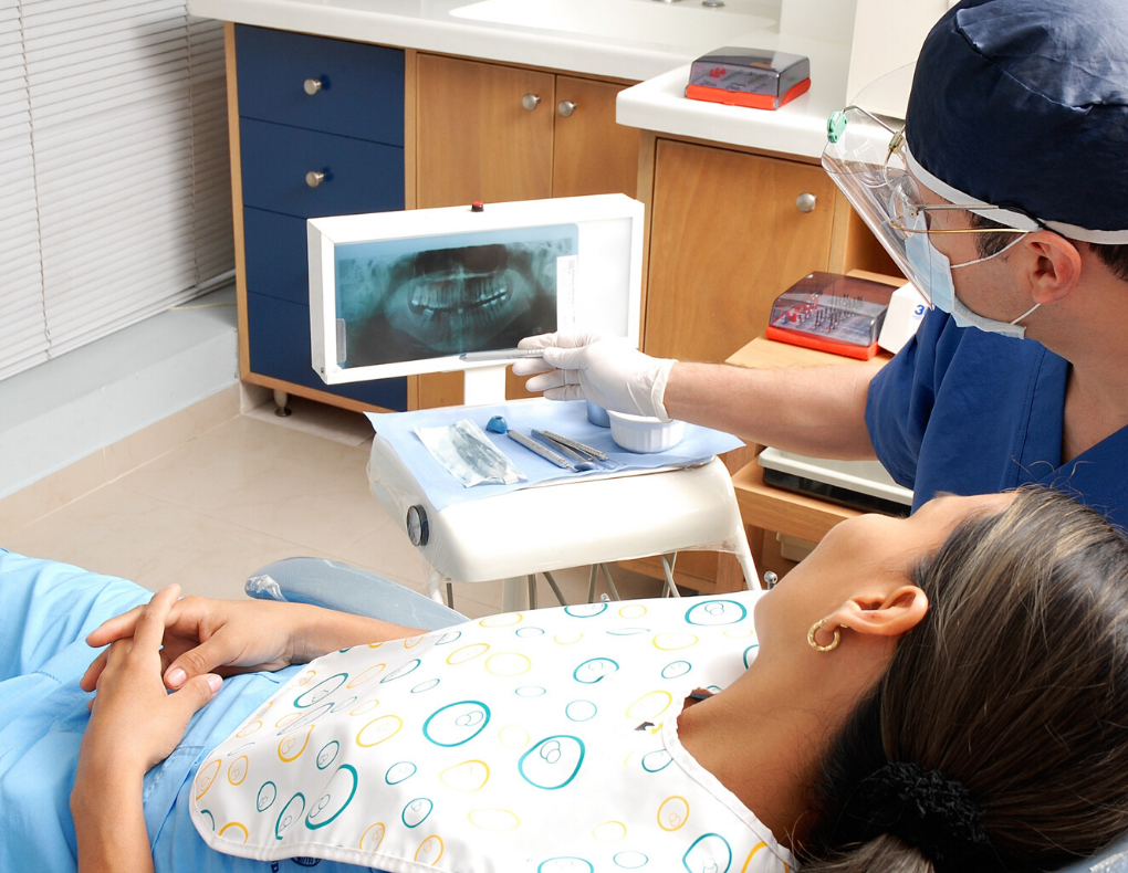 female patient with dentist wearing blue scrubs looking at dental xray for dental insurance