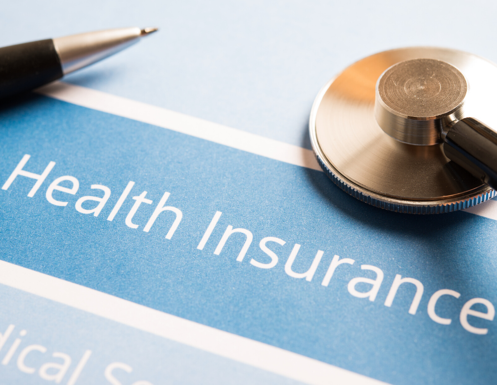 health insurance printed on paper with pen and stethoscope on top